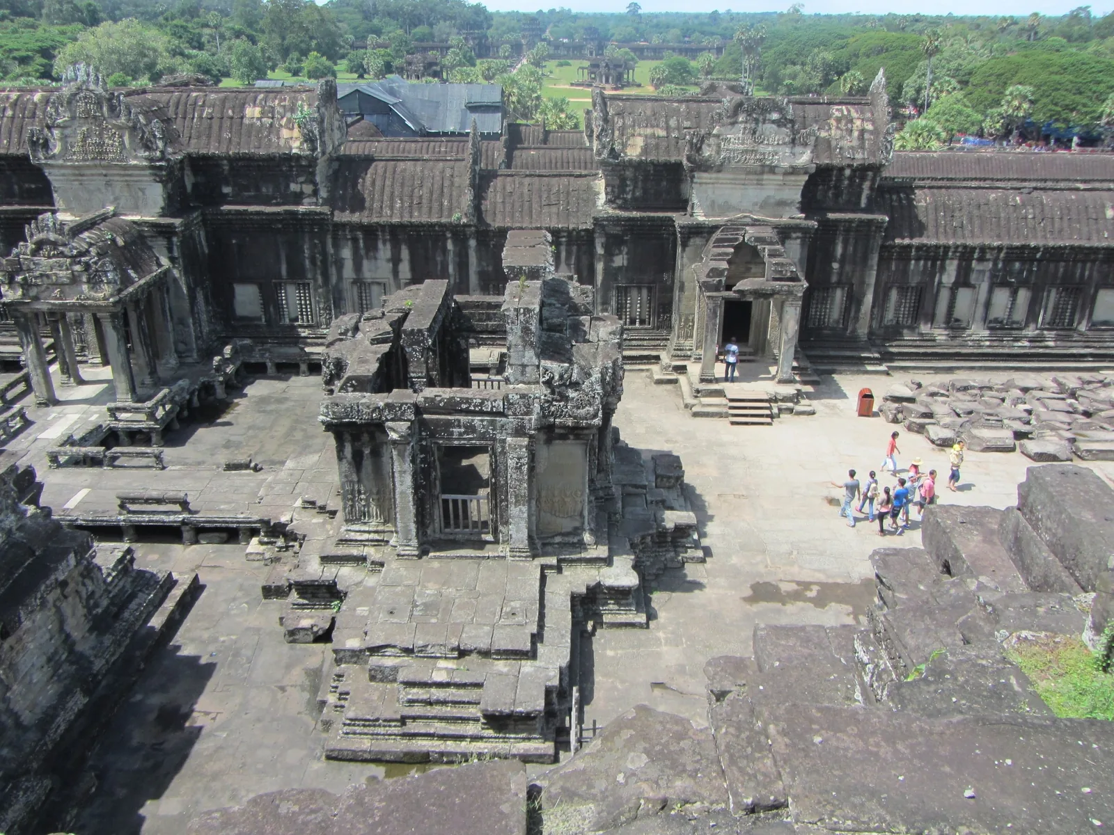 Elevated view of Angkor Wat's inner courtyard with weathered stone galleries and visitors walking below, Siem Reap.