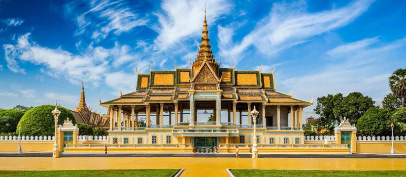 The tiered golden roofs of the Royal Palace behind its white wall in Phnom Penh