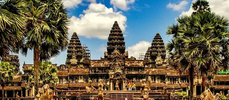 Angkor Wat’s five towers seen across the moat between tall sugar palms