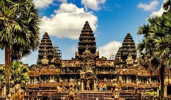 The stone causeway and towers of Angkor Wat under a bright midday sky