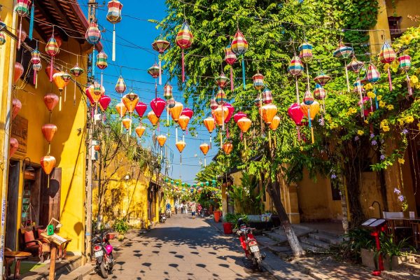 Silk lanterns strung above a lane of yellow shophouses in the old town of Hoi An