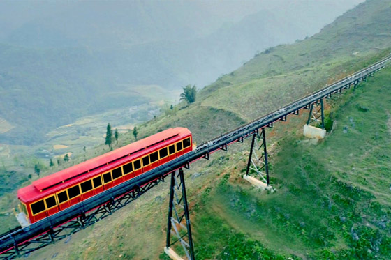 A red funicular carriage climbing a forested ridge in the mountains above Sa Pa