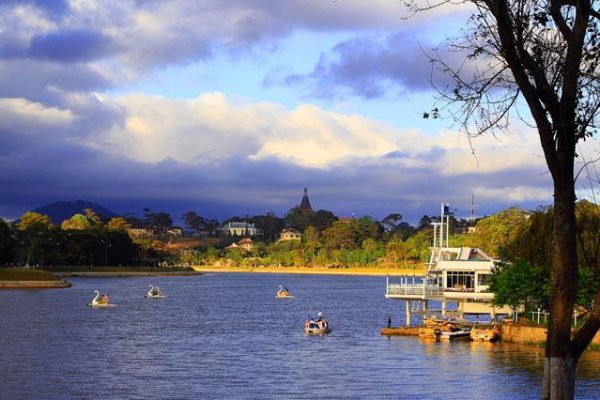 Rowing boats and a small passenger launch on a wide brown river lined with trees