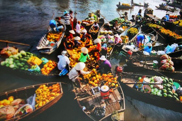Wooden boats loaded with fruit and vegetables trading alongside each other at a Mekong floating market